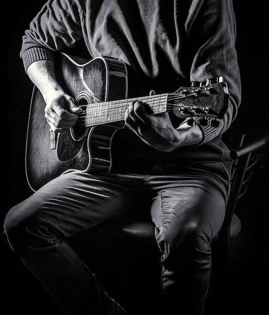 Male musician playing guitar, music instrument. Man's hands playing acoustic guitar, close up. Acoustic guitars playing. Music festival.