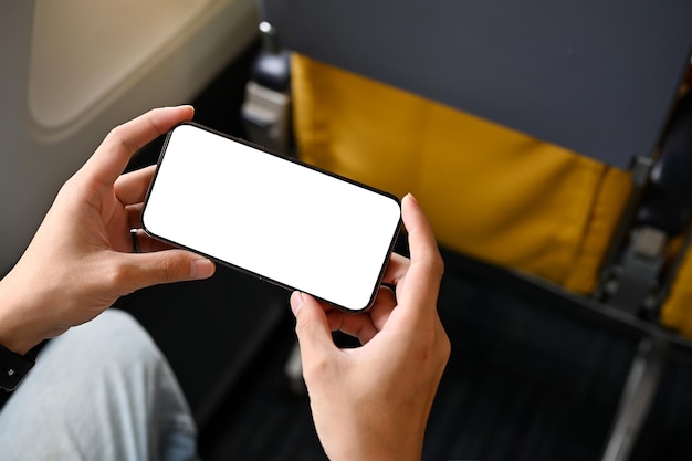 A male passenger using his smartphone during a flight phone white screen mockup