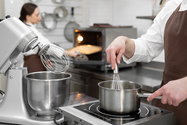 Male pastry chef cooks a berry kuli in a saucepan for filling a cake.