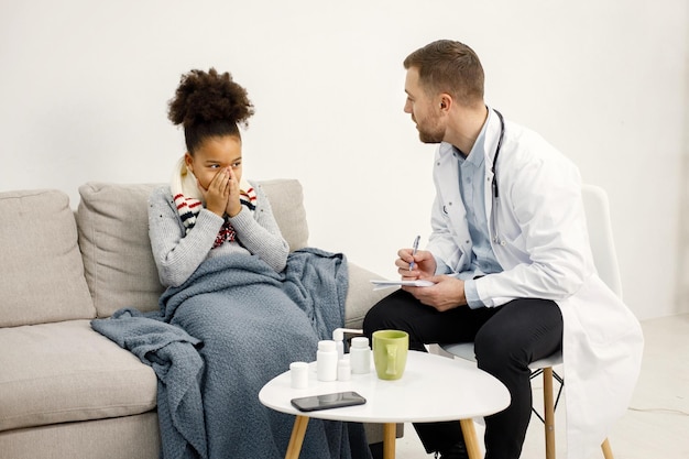 Male pediatrician examing sick little black girl