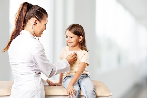 Male pediatrician hold stethoscope exam child boy patient visit doctor with mother,