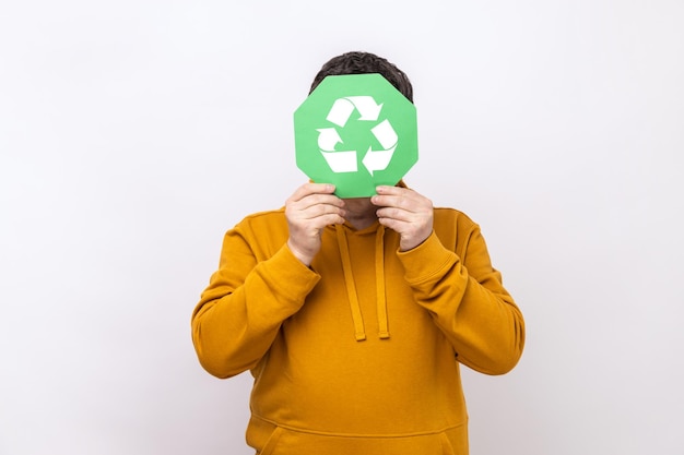 Male person hiding face behind green recycling sign garbage sorting and environment protection