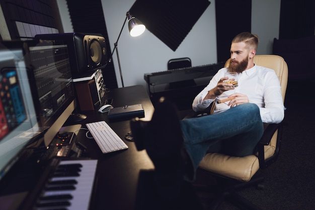 The male producer sits in the recording studio.