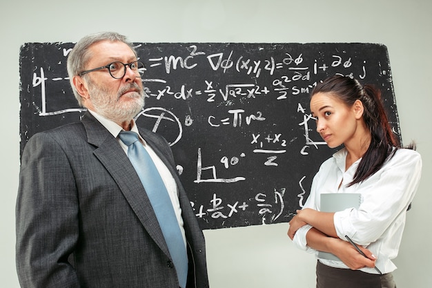 Male professor and young woman against chalkboard in classroom