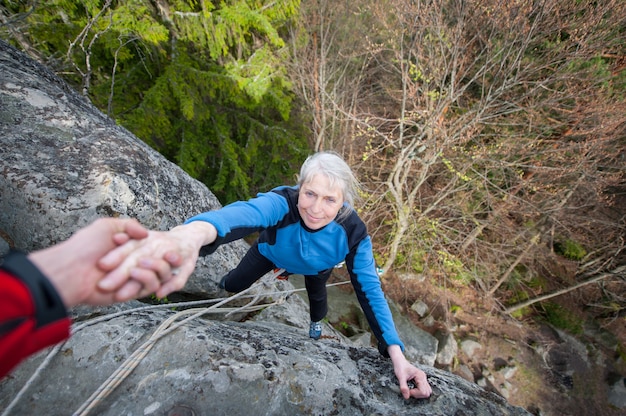 Male rockclimber is helping a climber female