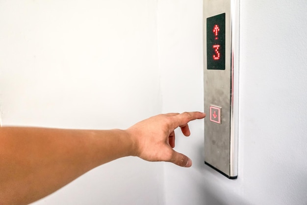 Male's hand pushs the down bottom on the dirty loading elevator that's behind for building