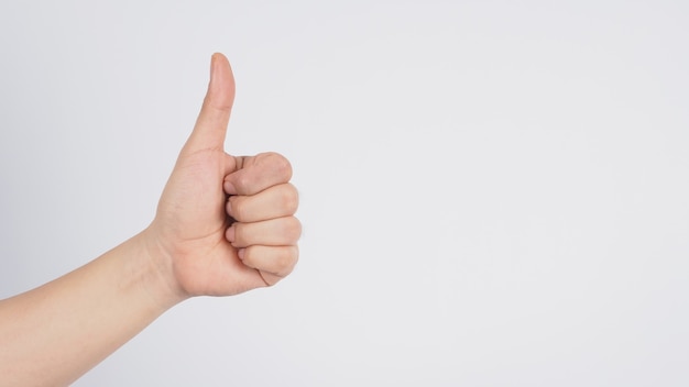 Male's left hand doing thumbs up sign on white background.