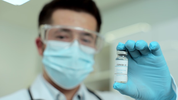 Male scientist holding ampoule in hand, new medication developing, vaccination from coronavirus infection.