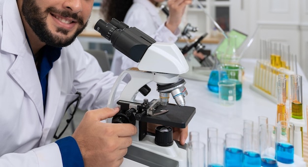 Male scientist in white lab coat working with microscope for research in medical laboratory