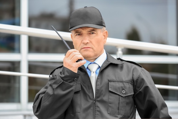 Male security guard using portable radio outdoors