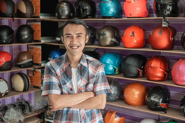 Male shop assistant smiling with crossed hands in helmets store