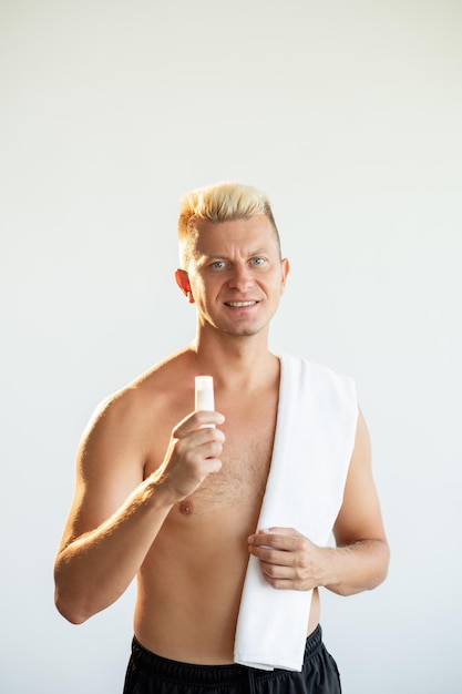 Male skincare Cosmetic product Body moisturizing Satisfied shirtless athletic blond man presenting small white tube with lotion or cream isolated on neutral copy space advertising background