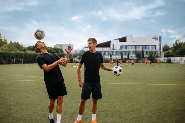 Male soccer players training with balls on the field. Footballers on outdoor stadium, team workout before game