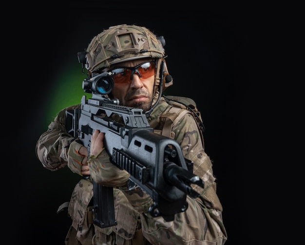 A male soldier in military clothes with a weapon on a dark background