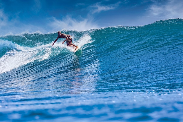 Male surfer on a blue wave at sunny day