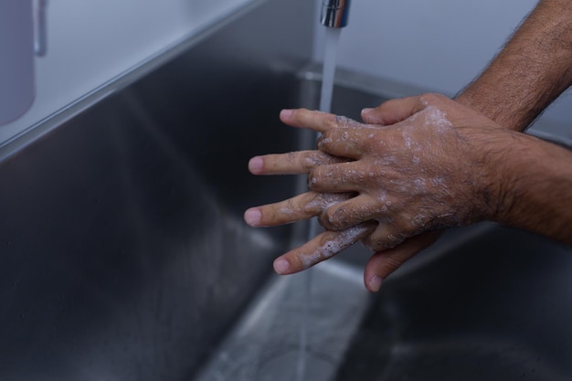 Male surgeon washing hands in sink at hospital