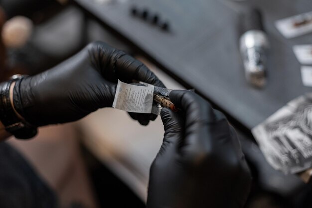 Male tattoo artist prepares for work and takes out a needle.