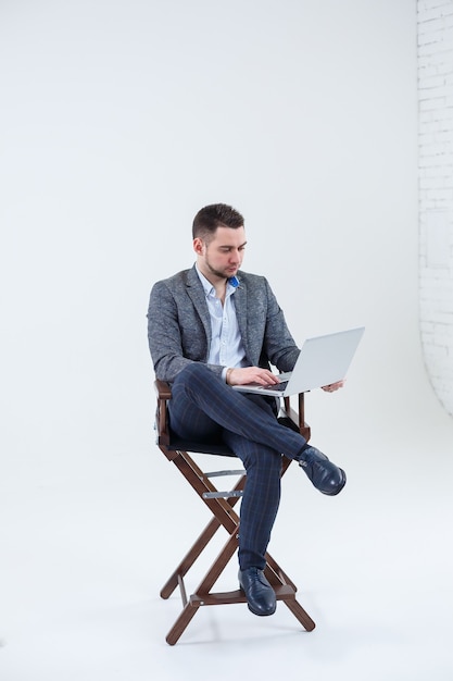 Male teacher director businessman sitting on a chair studying documents. He is looking at the laptop screen. New business project.