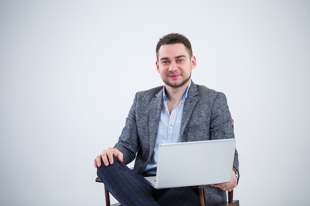 Male teacher director businessman sitting on a chair studying documents. He is looking at the laptop screen. New business project.