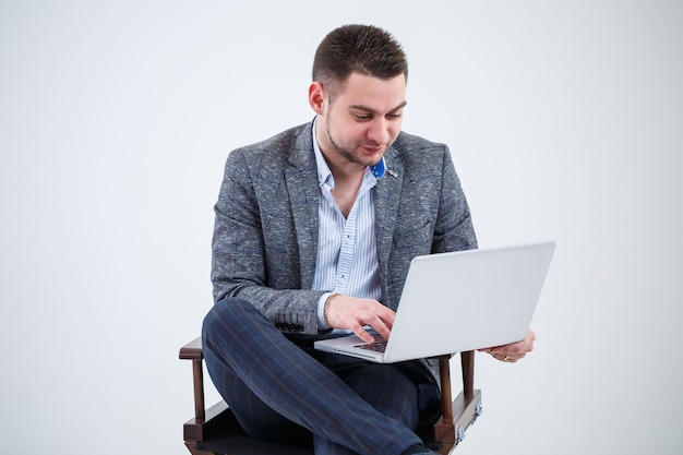 Male teacher director businessman sitting on a chair studying documents. He is looking at the laptop screen. New business project.