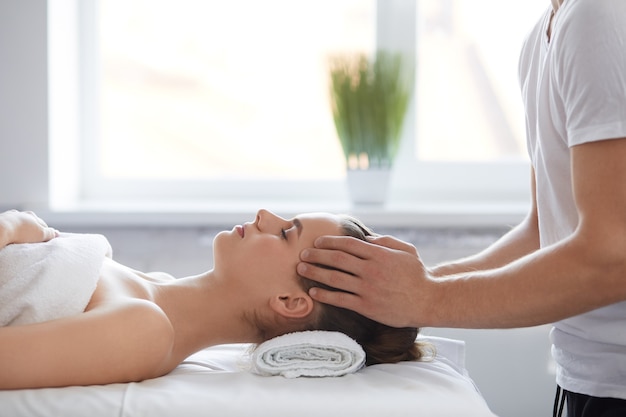 Male therapist making head massage to female client.