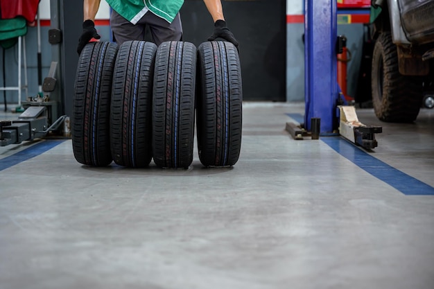 Male tire changer In the process of bringing 4 new tires that are in stock in order to change the wheels of the car at a service center or an auto repair shop for the automobile industry