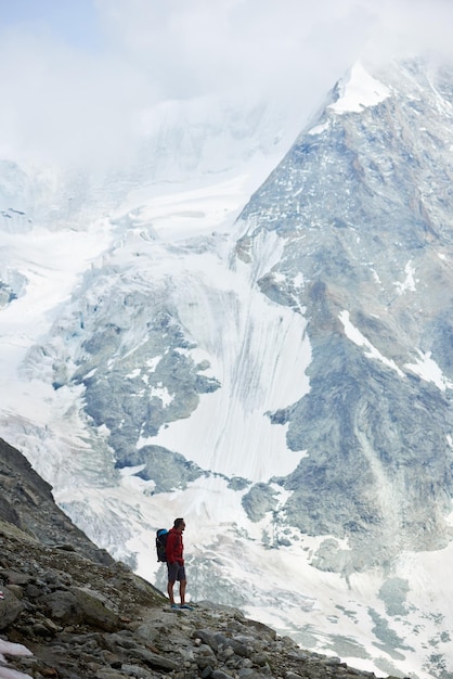 Male tourist climbing snowy rocky cliffs of beautiful Penning Alps in Switzerland