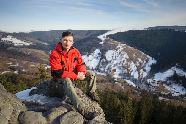 Male tourist sitting on rock on top of the mountain