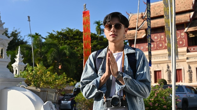 Male traveler standing and putting his hands together in a prayer position over beautiful temple