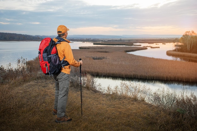 Male traveller with backpack on autumnal background Man hiking and enjoying beautiful autumn nature at sunrise