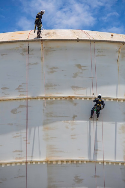 Male two worker inspection wearing safety first harness rope safety line working at a high place on tank roof spherical