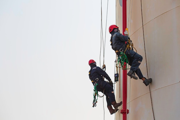 Male two worker rope access height safety inspection of thickness storage oil and gas tank industry