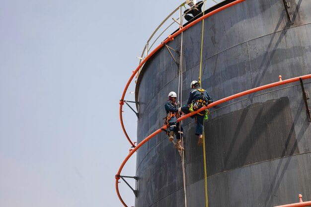 Male two worker rope down access safety inspection of pipe fire water repair storage tank