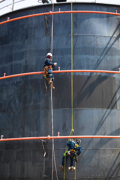 Male two worker rope down access safety inspection of pipe fire water repair storage tank