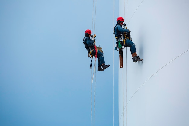 Male two workers down height tank rope access inspection of thickness shell plate storage tank gas propane safety work at height.