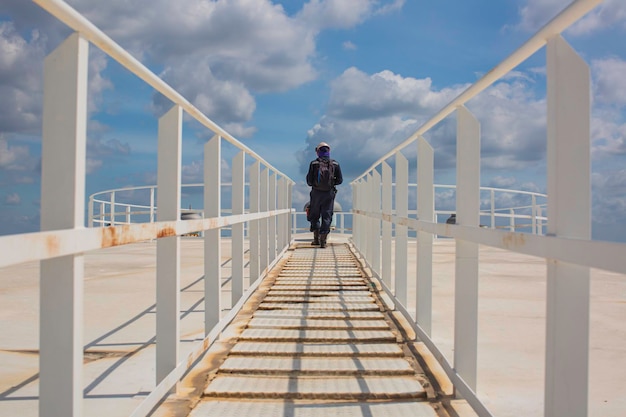 Male walking the up stairway inspection visual record stairs on the tank roof white