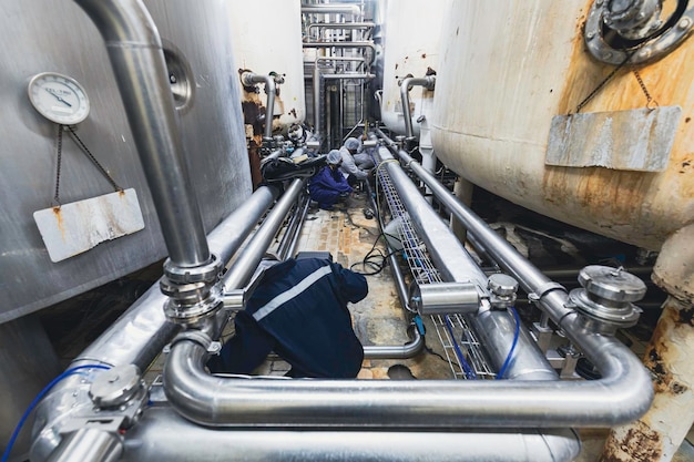 Male work inspection process stainless steel tanks and pipe with pressure meter in equipment tank facility for milk cellar at the with vertical stainless mixing tank