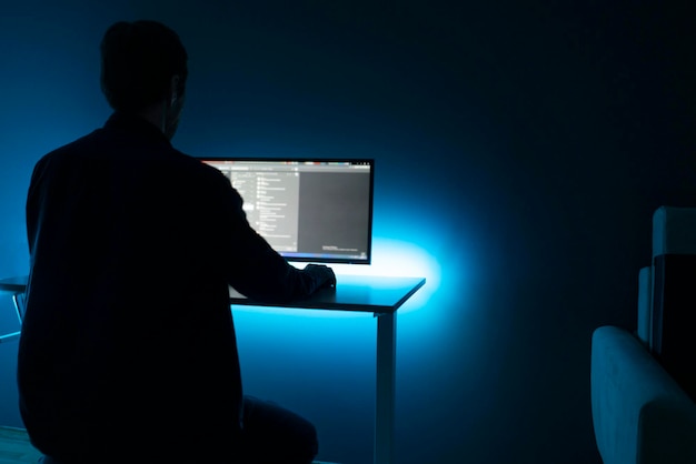 A male worker doing job on computer late in the night at home