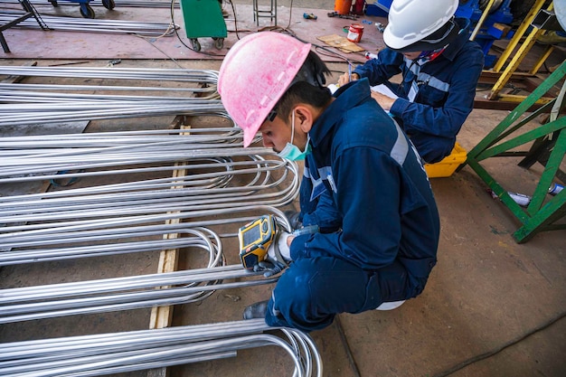 Male worker inspecting surface on heat exchanger tube bundle industrial construction warehouse positive