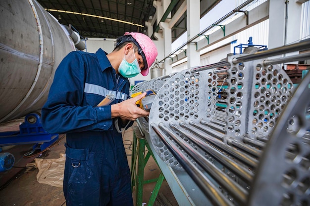 Male worker inspecting surface on heat exchanger tube bundle industrial construction warehouse positive