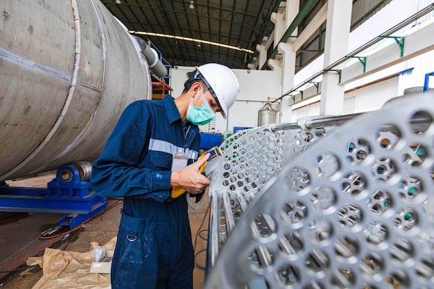 Male worker inspecting surface on heat exchanger tube bundle industrial construction warehouse positive