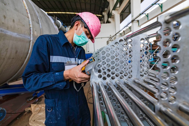 Male worker inspecting surface on heat exchanger tube bundle industrial construction warehouse positive