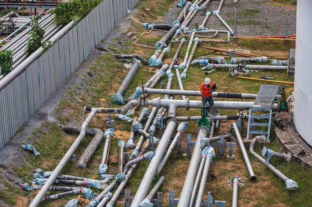 Male worker inspection at steel long pipes and pipe elbow cutting in new construction station oil factory during refinery valve of visual check record pipeline