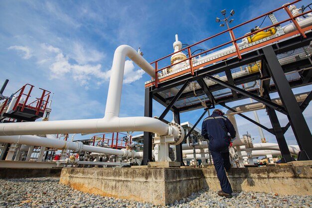 Male worker inspection at steel long pipes and pipe elbow in station oil factory during refinery valve of visual check record pipeline oil and gas industry.