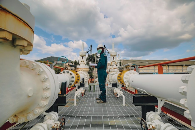 Male worker inspection at steel long pipes and pipe elbow in station oil factory during refinery valve of visual check record pipeline tank oil and gas