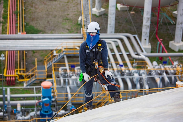 Male worker inspection wearing safety first harness rope safety line working at a high place on tank roof spherical gas