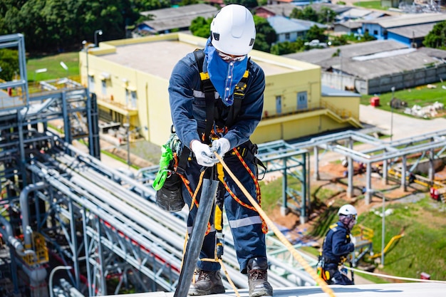 Male worker inspection wearing safety first harness rope safety line working at a high place on tank roof spherical gas