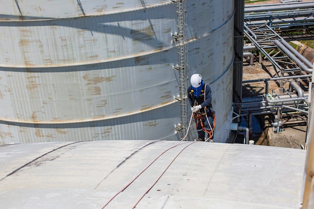 Male worker inspection wearing safety first harness rope safety line working at a high place on tank roof spherical gas