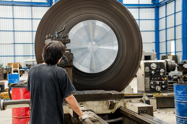 Male worker is working on a CNC milling machine in the metal industry.