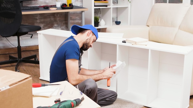 Male worker listening instructions on mobile phone for furniture assembly.